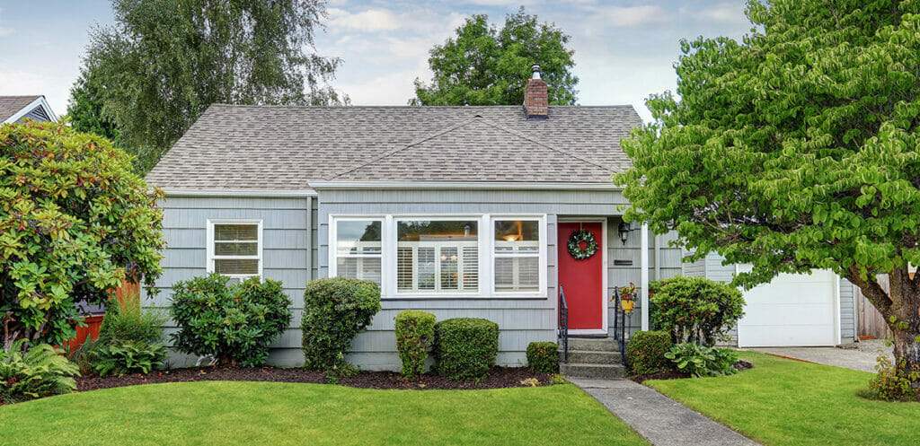 A home with a well manicured lawn and a red door